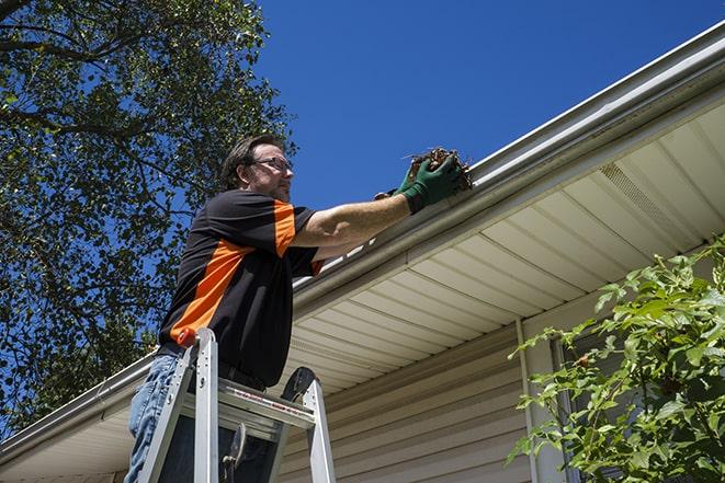 a worker on a rooftop repairing gutters and downspouts in Bagdad FL